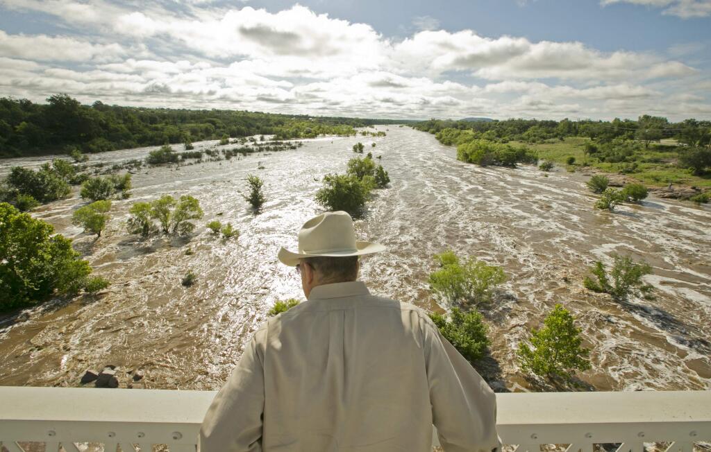 Tex Toler watches the Llano River rise in Llano, Texas, on Friday, May 29, 2015, after another round of heavy rains. Officials are closely monitoring the levels of rivers in Texas engorged by the deluge of last weekend. (AP Photo/Austin American-Statesman, Jay Janner)