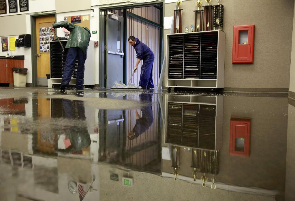 Mitchell Samios, left, and John Salus, Petaluma school district maintenance employees, clean up the band room after it flooded with water due to heavy rain on Wednesday, December 3, 2014 in Petaluma, California . (BETH SCHLANKER/ The Press Democrat)