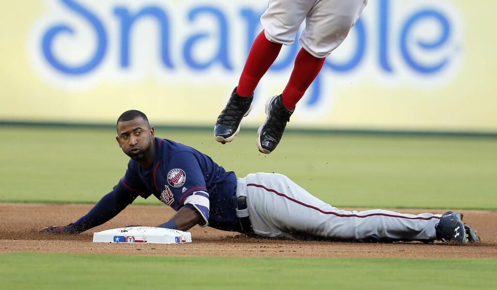 Texas Rangers second baseman Rougned Odor, top, goes up for an overthrow as Minnesota Twins' Eduardo Nunez (9) slides safely into the bag for a double in the first inning of a baseball game, Thursday, July 7, 2016, in Arlington, Texas. (AP Photo/Tony Gutierrez)