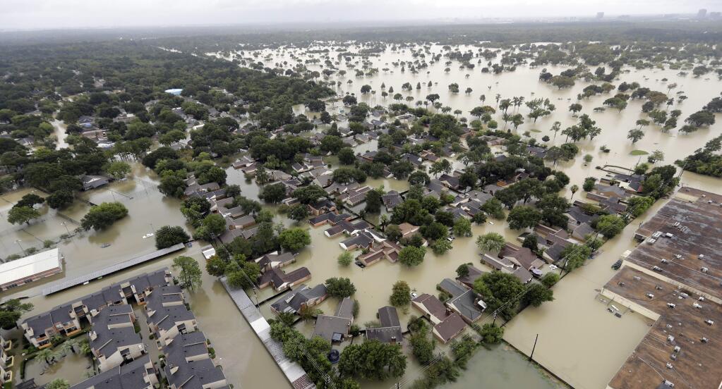 FILE - In this Aug. 29, 2017 aerial file photo, a neighborhood near Addicks Reservoir are flooded by rain from Harvey, in Houston. Houston's population is growing quickly, but when Harvey hit last weekend there were far fewer homes and other properties in the area with flood insurance than just five years ago, according to an Associated Press investigation. (AP Photo/David J. Phillip, File)