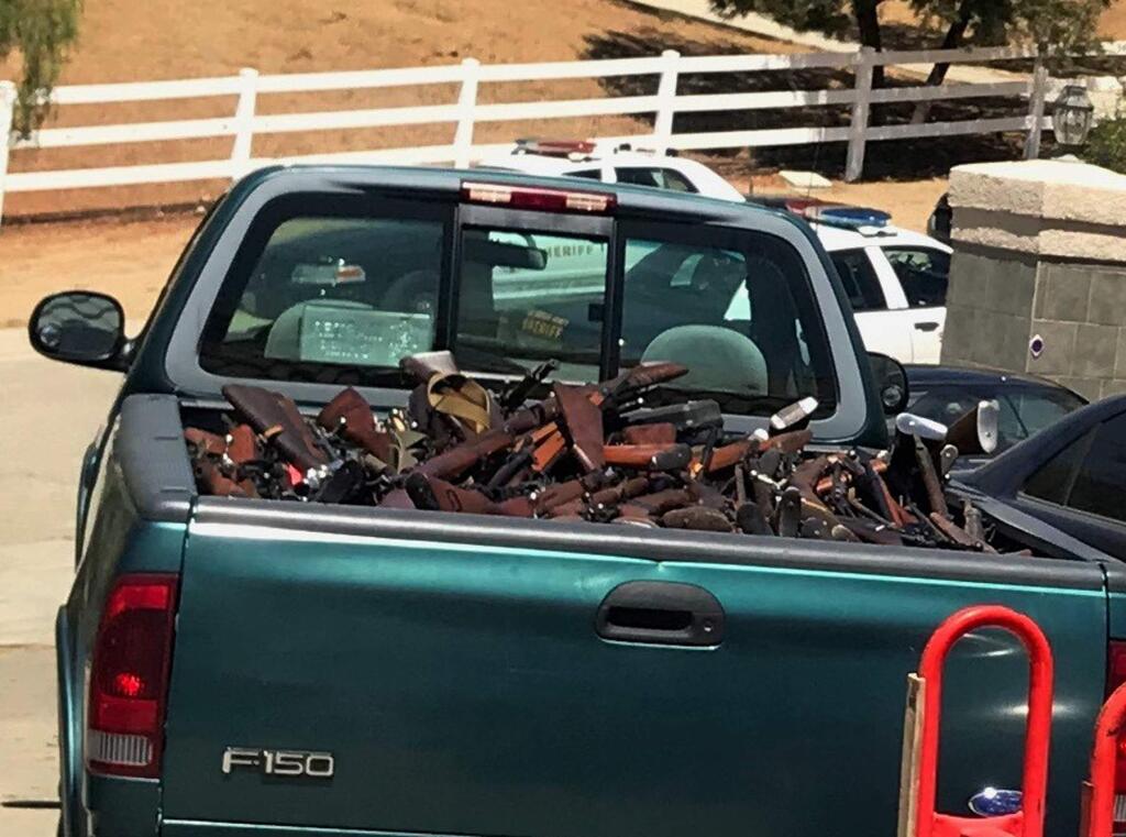 This June 2018 photo provided by the Los Angeles County Sheriff's Department shows over 550 firearms that Los Angeles County sheriff's deputies and state and federal investigators seized at homes in Agua Dulce, Calif. Authorities have seized the guns at two Southern California homes and made one arrest after getting a tip that a convicted felon was storing an arsenal. (Los Angeles County Sheriff's Department via AP)
