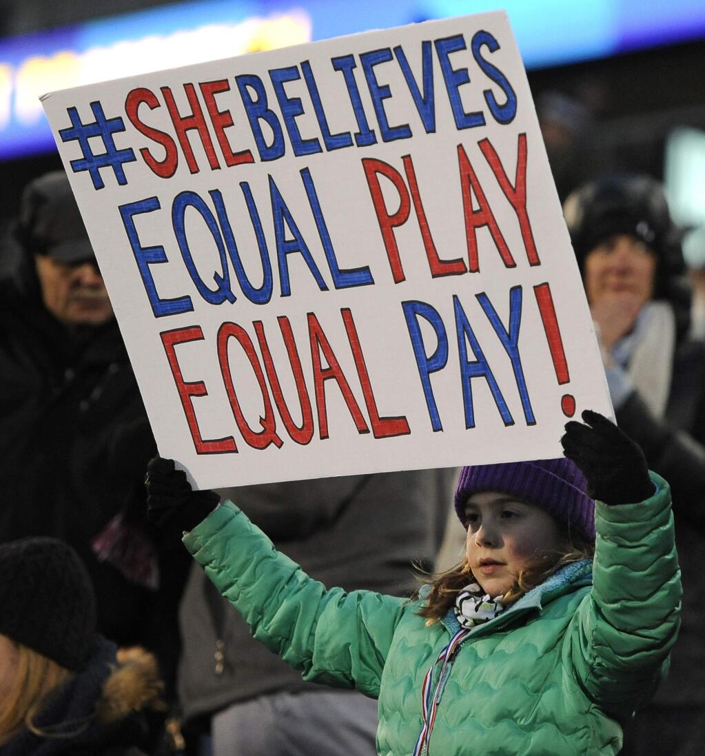 FILE - In this April 6, 2016, file photo, a girl holds up a sign for equal pay for the U.S. women soccer players, during the first half of an international friendly soccer match between the United States and Colombia, in East Hartford, Conn. Players for the World Cup champion women's national team say mediation talks with the U.S. Soccer Federation over equal pay are over. Molly Levinson, who represents the players in matters concerning the dispute, said in a statement Wednesday, Aug. 14, 2019, that the players look forward to a jury trial. (AP Photo/Jessica Hill, File)