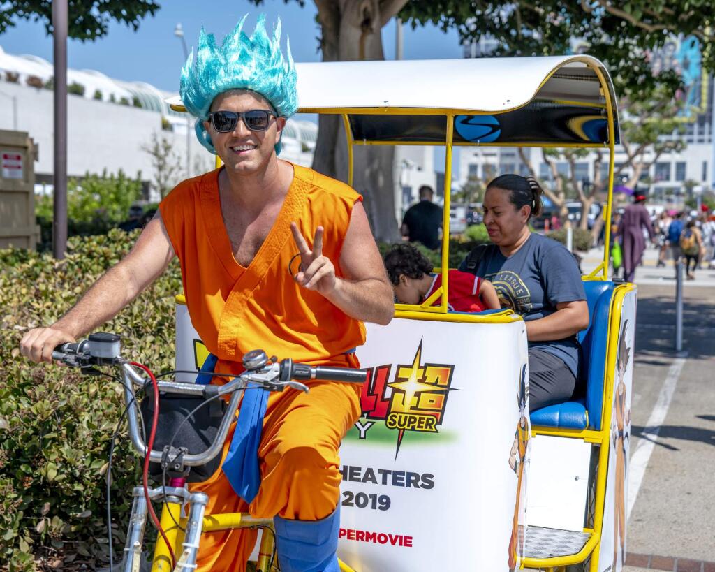 FILE - In this July 20, 2018 file photo, a pedicab driver dressed as a character from the anime franchise 'Dragon Ball' gestures as he carries passengers during Comic-Con International in San Diego. 'Dragon Ball” is a revered anime that has influenced pop culture for years, earning praise from the likes of Michael B. Jordan, Ronda Rousey and Chris Brown, showing up in end zone celebrations and even at the Macy's Thanksgiving Day Parade. With the new film 'Dragon Ball Super: Broly' releasing this week in the U.S., the franchise's popularity with its famous and non-famous fans is likely to grow. (Photo by Christy Radecic/Invision/AP, File)