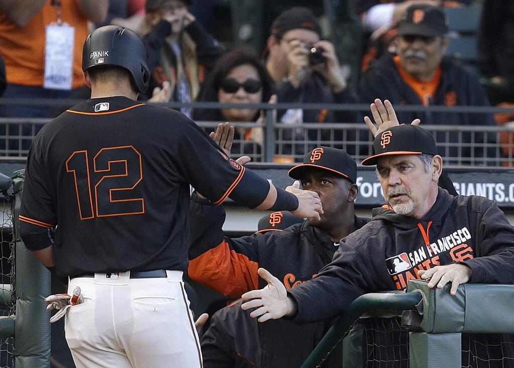 San Francisco Giants' Joe Panik (12) is congratulated by manager Bruce Bochy, right, after scoring against the Miami Marlins during the first inning of a baseball game Saturday, April 23, 2016, in San Francisco. Panik scored on a single by Buster Posey. (AP Photo/Ben Margot)