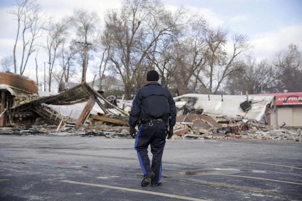 A member of the Missouri Highway Patrol walks past a building burned to the ground, Tuesday, Nov. 25, 2014, in Dellwood, Mo. The building and several others in-and-around Ferguson were burned during protests after a grand jury decided not to indict a Ferguson police officer in the shooting death of Michael Brown. (AP Photo/Jeff Roberson)