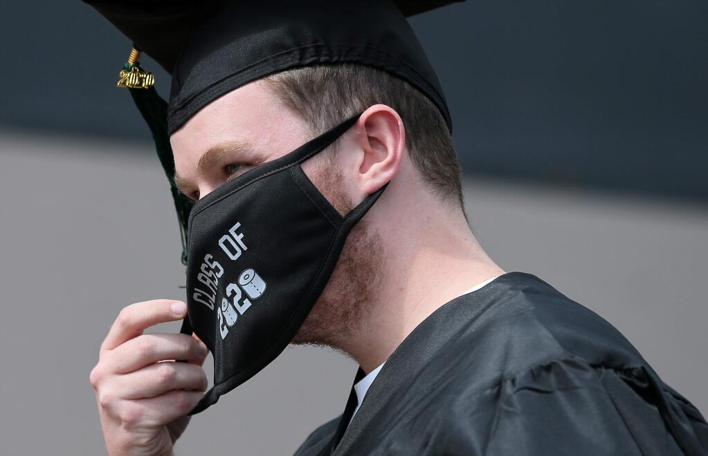 Roman Hutchison adjusts his mask while participating in the drive-thru commencement ceremony at Maria Carrillo High School, in Santa Rosa on Friday, May 29, 2020. (Christopher Chung/ The Press Democrat)