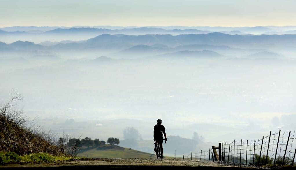 Chris Monson of Petaluma rides down Sonoma Mountain Road into a valley of smog on Tuesday, Jan. 6, 2015. (KENT PORTER/ PD)