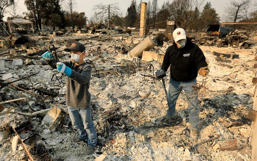Santa Rosa firefighter Tony Niel and his son Jordon, 13, sift through the debris of their home in Larkfield, Wednesday Oct. 18, 2017. Niel and his family evacuated from their home as the Tubbs fire bore down on their neighborhood last week. After making sure his children and wife were safe, Niel headed in to work to help fight the fires in Coffey Park. (Kent Porter / Press Democrat) 2017