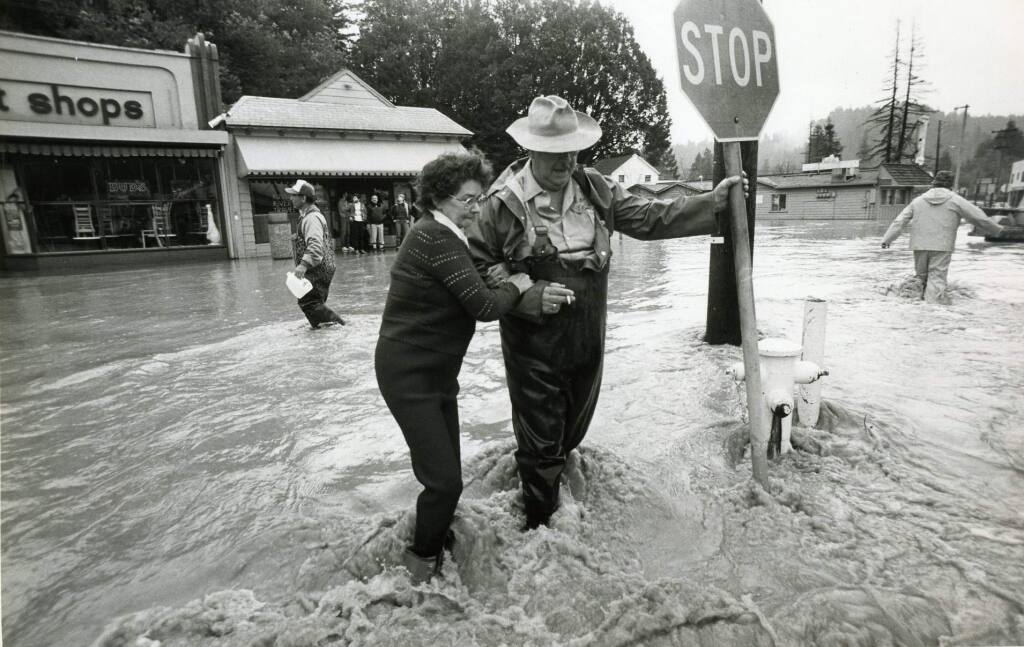In this 1986 file photo, Bonnie King helps her husband Grant make it across Main Street in Guerneville during a flood. (Chris Dawson / PD File)