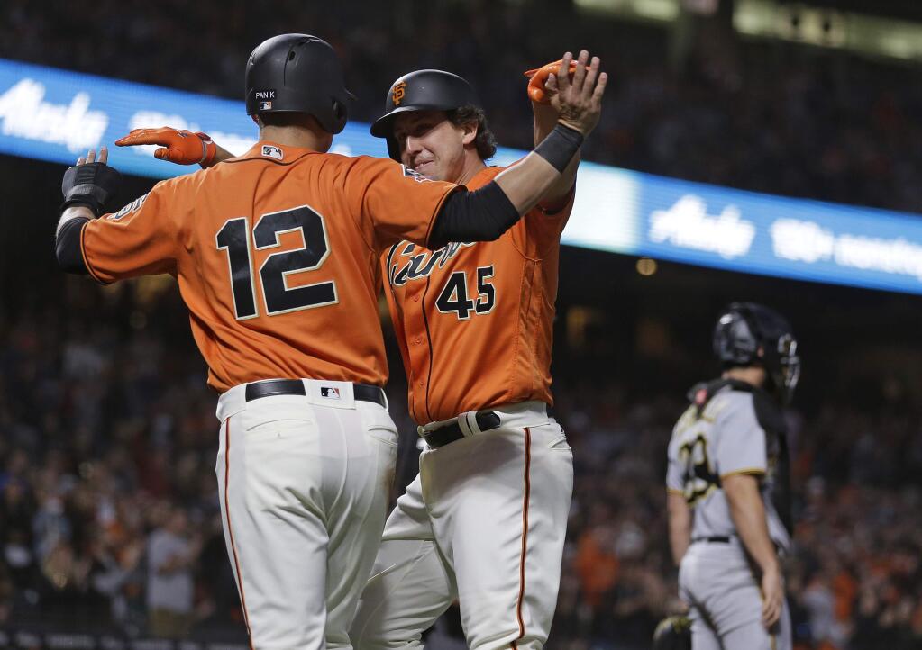 San Francisco Giants' Derek Holland is greeted by teammate Joe Panik, left, after they scored in the third inning against the Pittsburgh Pirates on Friday, Aug. 10, 2018, in San Francisco. The pair scored after Buster Posey singled to center field. At right is Pirates catcher Francisco Cervelli. (AP Photo/Eric Risberg)