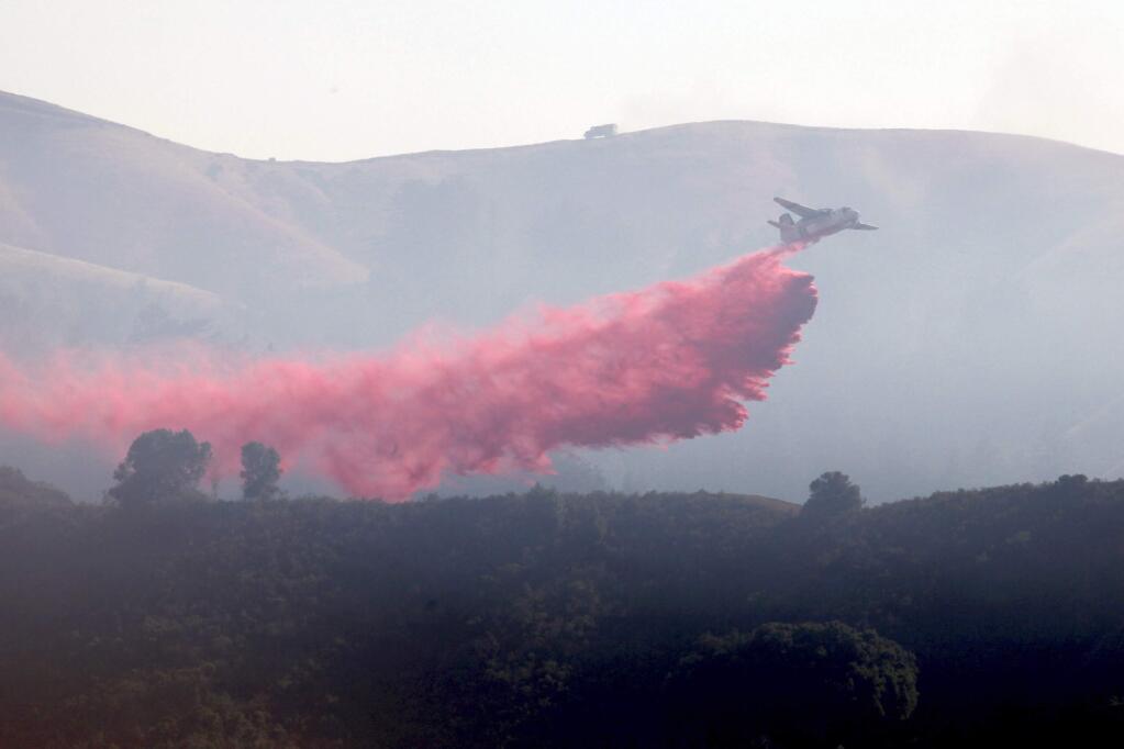 File - In this July 28, 2016 file photo, a plane drops fire retardant on a wildfire in Carmel Valley, Calif. A wildfire burning for nearly two months on California's Central Coast has surpassed $200 million in firefighting costs, becoming the costliest to fight in U.S. history. Data from the National Interagency Fire Center released Monday, Sept. 19, 2016, says the so-called Soberanes fire has cost $206.7 million to fight so far. (Nic Coury/Monterey County Weekly via AP, File)