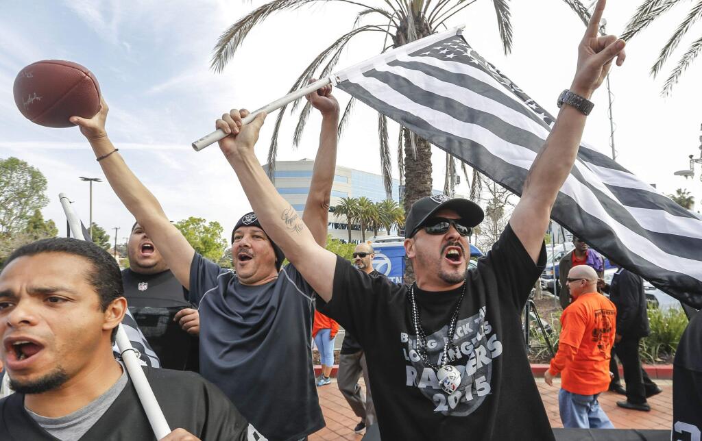 Raiders fan Sergio Gutierrez, right, joins football fans celebrating a proposed NFL football stadium by the owners of the Raiders and San Diego Chargers in Carson on Friday. (Damian Dovarganes / Associated Press)