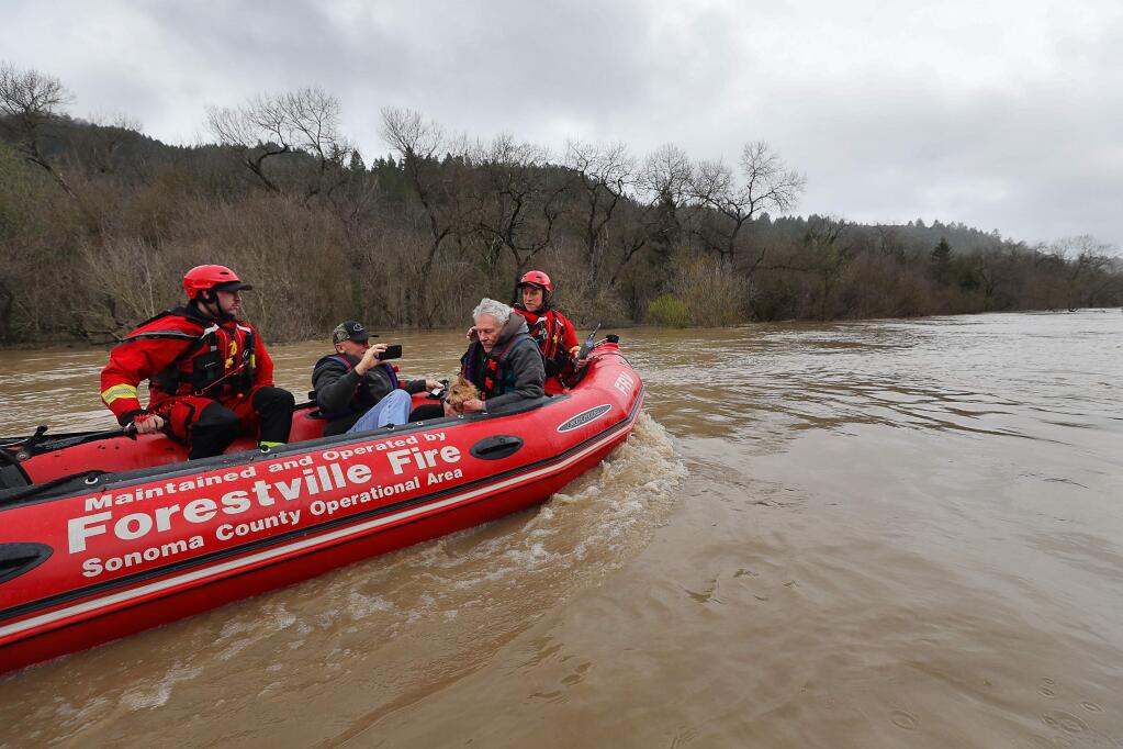 Forestville Fire Department engineers Spencer Hansen, left, and Eric Gromala, right, evacuate Brian Peddinghaus, second from left, and Jack Hulsey up the Russian River after retrieving them from their home on River Drive near Forestville on Wednesday, February 27, 2019. (Christopher Chung/ The Press Democrat)