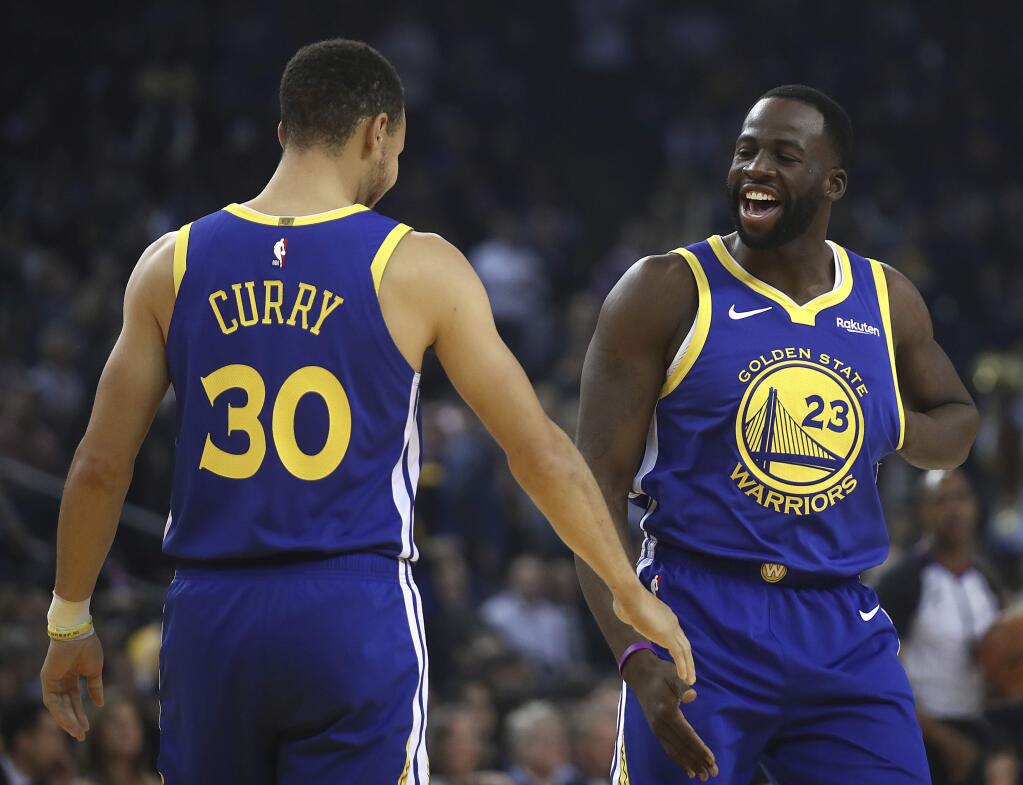 Golden State Warriors' Draymond Green, right, greets Stephen Curry (30) prior to the first half of an NBA basketball game against the Minnesota Timberwolves Monday, Dec. 10, 2018, in Oakland, Calif. The first game both have retuned to play at home since recovering from injuries. (AP Photo/Ben Margot)