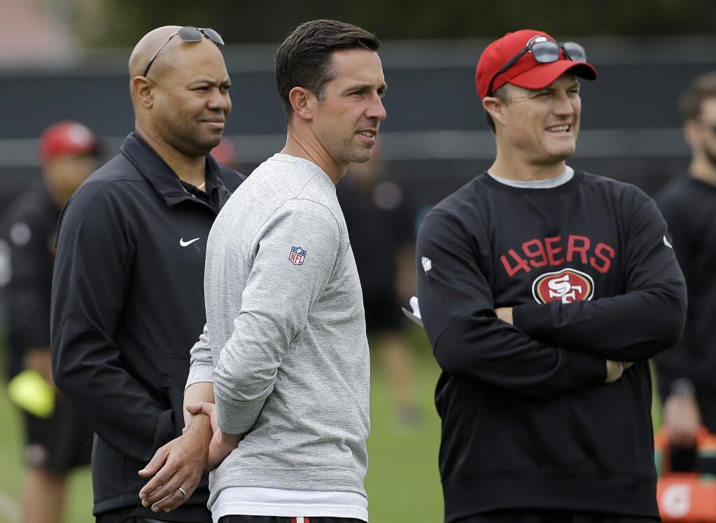 San Francisco 49ers head coach Kyle Shanahan, center, watches as players warm up with general manager John Lynch, right, and Stanford head coach David Shaw during the 49ers organized team activity at its training facility in Santa Clara, Thursday, June 8, 2017. (AP Photo/Jeff Chiu)