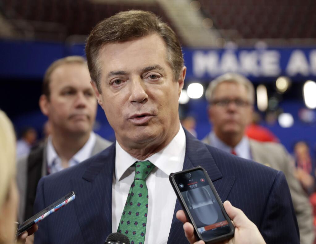 FILE - In this July 17, 2016 file photo, then-Trump Campaign Chairman Paul Manafort talks to reporters on the floor of the Republican National Convention at Quicken Loans Arena in Cleveland as Rick Gates listens at back left. Manafort, said during the presidential race that he was willing to provide “private briefings” for a Russian billionaire the U.S. government considers close to Russian President Vladimir Putin. That's according to a July 2016 email exchange Manafort wrote to a former employee of his political consulting firm about offering to brief Russian billionaire Oleg Deripaska. (AP Photo/Matt Rourke, File)