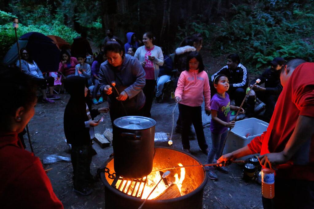 Children and adults roast marshmallows around a fire and sing songs in Spanish during a Latino Outdoors camp out at the Pomo Canyon Environmental Campground near Duncans Mills on Saturday, September 5, 2015. (Alvin Jornada / The Press Democrat)