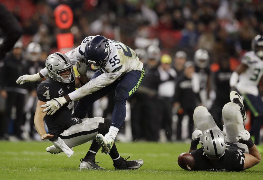 In this Oct. 14, 2018, file photo, Oakland Raiders quarterback Derek Carr (4) is sacked by Seattle Seahawks defensive end Frank Clark (55) during the second half at Wembley stadium in London. After being well protected his first four seasons, Carr has been under heavy pressure the past few weeks and the results have not been good. (AP Photo/Matt Dunham, File)