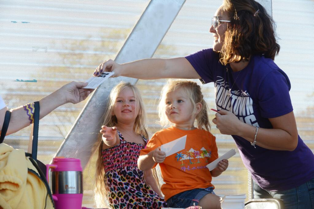 Erika Galvan of Middletown, far right, greets attendees with her daughters Camila, 2 (center) and Trinity, 4, before the start of the Middletown High School football team's first home game since the recent catastrophic Valley fire. The Galvan family lost their home in the recent fire and are currently living on their property in a trailer they recently purchased. (Erik Castro/for The Press Democrat)