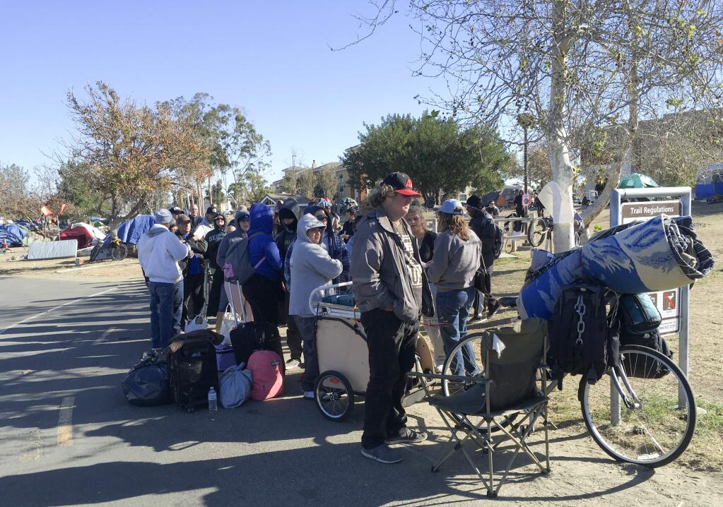 Homeless people line up in preparation to move from their homeless camp site along a riverbed in Anaheim, Calif. on Tuesday, Feb. 20, 2018. Authorities are being allowed to shut down a large homeless encampment in Southern California and move hundreds of tent-dwellers into motel rooms. (AP Photo/Amy Taxin)