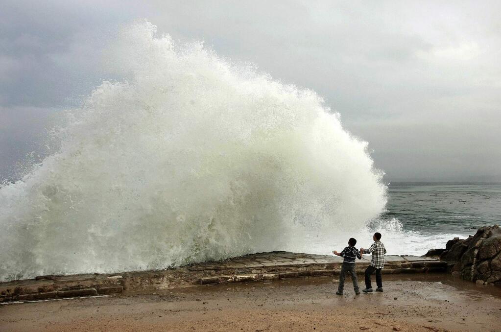 Aidan Stephenson,12, and Conor Stephenson,10, visiting from Phoenix, watch the waves break on Ocean View Boulevard, Wednesday, Dec. 10, 2014, in Pacific Grove, Calif. Northern California residents are bracing for a powerful storm that could be the biggest in five years and which prompted the National Weather Service to issue a high wind and flash flood warning. The storm is expected to arrive Wednesday and pelt the region through Thursday. (AP Photo/Monterey Herald, Vern Fisher)