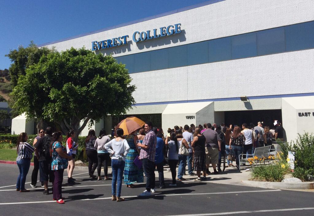 Students wait outside Everest College, Tuesday, April, 28, 2015 in Industry, Calif., hoping to get their transcriptions and information on loan forgiveness and transferring credits to other schools. Corinthian Colleges shut down all of its remaining 28 ground campuses on Monday, April 27, displacing 16,000 students. The shutdown comes less than two weeks after the U.S. Department of Education announcing it was fining the for-profit institution $30 million for misrepresentation. (AP Photo/Christine Armario)