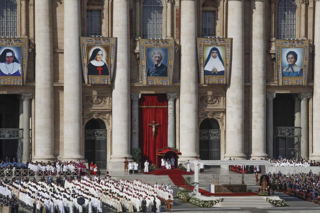 Tapestries hanging from the facade of St. Peter's Basilica portray from left, Dulce Lopes Pontes, Giuseppina Vannini, John Henry Newman, Maria Teresa Chiramel Mankidiyan, and Margarita Bays, as Pope Francis presides over a canonization Mass, at the Vatican, Sunday, Oct. 13, 2019. Pope Francis canonized Cardinal John Henry Newman, the 19th-century Anglican convert who became an immensely influential, unifying figure in both the Anglican and Catholic churches. Francis presided over Mass on Sunday in a packed St. Peter's Square to declare Newman and four women saints. (AP Photo/Alessandra Tarantino)
