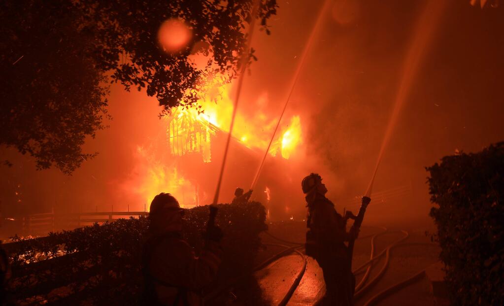 Downey firefighters concentrate on wetting down a house adjacent to a burning barn, Sunday Oct. 27, 2019, as the Kincade fire pushed down to Shiloh Ridge and Faught Road east of Windsor. (KENT PORTER/ PD)