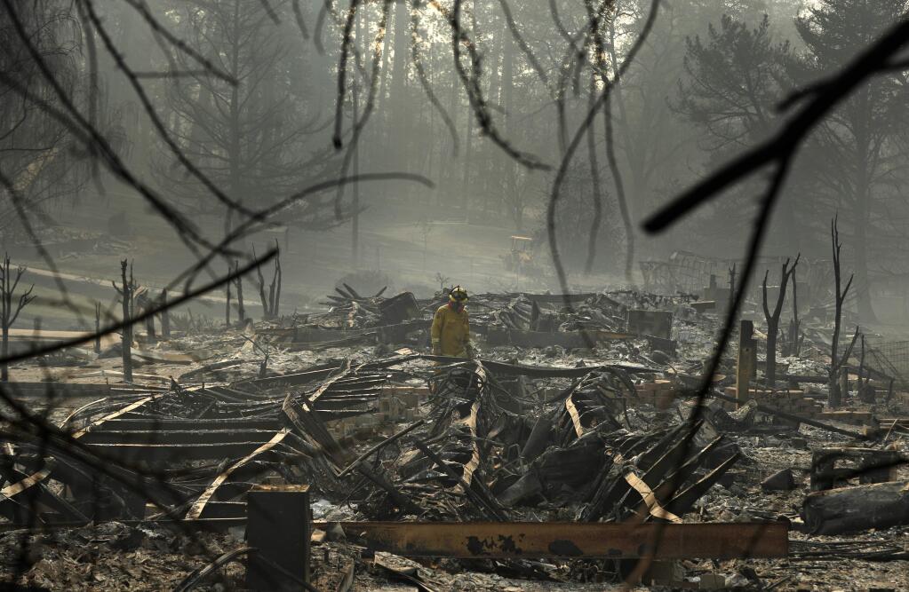 A firefighter searches for human remains in a trailer park destroyed in the Camp Fire, Friday, Nov. 16, 2018, in Paradise, Calif. (AP Photo/John Locher)