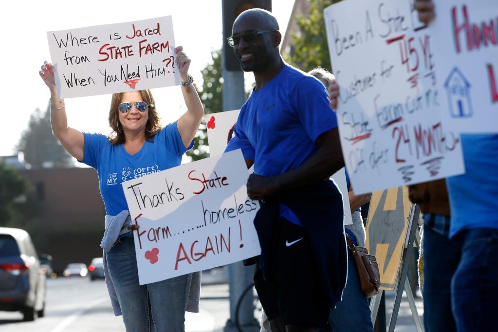 Fire survivors LuAnn Scally, left, and Quincy King, both residents of Coffey Park, carry signs during a rally in support for fire survivors who will be losing their insurance coverage at the second anniversary of the North Bay wildfires, at Old Courthouse Square in Santa Rosa, California, on Friday, September 27, 2019. (Alvin Jornada / The Press Democrat)
