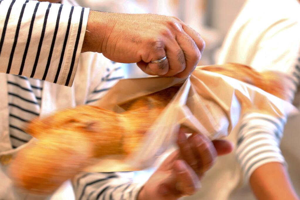 Nas Salamati wraps an epi baguette for a customer at Goguette Bread in Santa Rosa, California, on Wednesday, July 18, 2018. (Alvin Jornada / The Press Democrat)