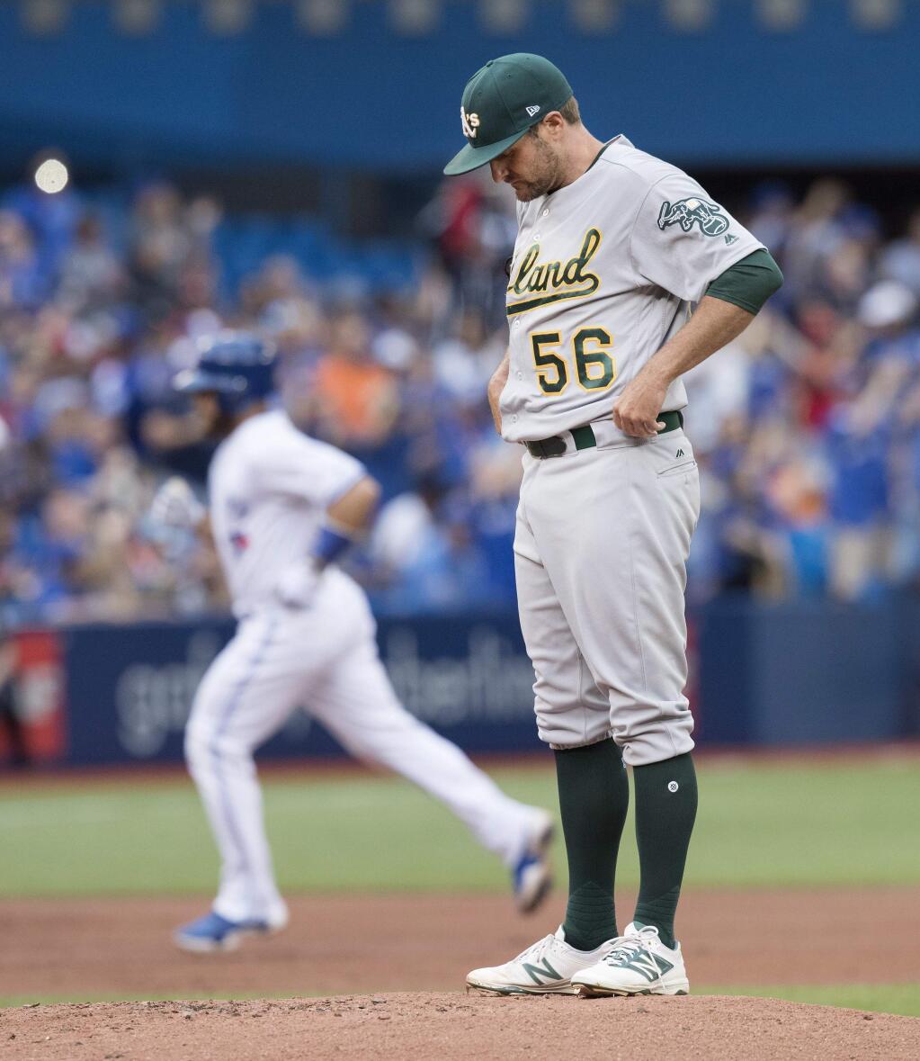 Oakland Athletics starting pitcher Chris Smith looks down at the mound after giving up a home run to Toronto Blue Jays Russell Martin, back left, during first-inning baseball game action in Toronto, Monday, July 24, 2017. (Fred Thornhill/The Canadian Press via AP)