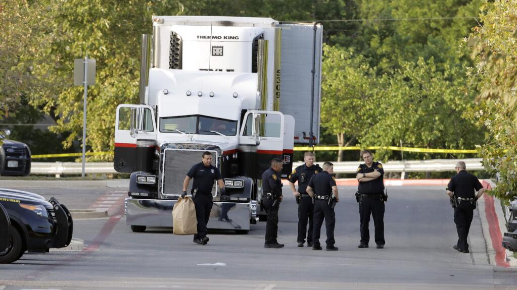 San Antonio police officers investigate the scene Sunday, July 23, 2017, where eight people were found dead in a tractor-trailer loaded with at least 30 others outside a Walmart store in stifling summer heat in what police are calling a horrific human trafficking case, in San Antonio. (AP Photo/Eric Gay)