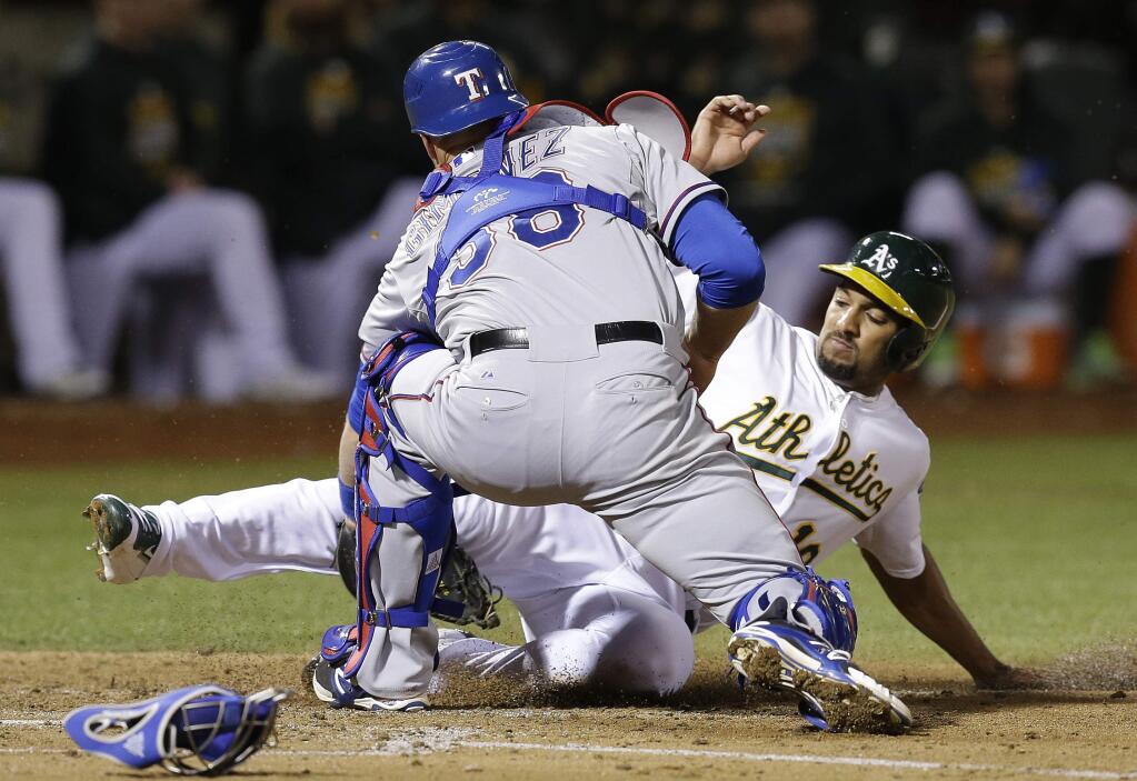 Texas Rangers catcher Chris Gimenez, left, tags out Oakland Athletics' Marcus Semien during the second inning of a baseball game Tuesday, Sept. 22, 2015, in Oakland, Calif. Semien was attempting to score on a bunt by Billy Burns. (AP Photo/Ben Margot)