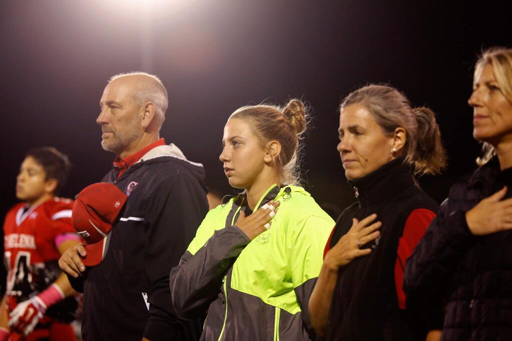 Saint Helena's Maddie Wagner, center in yellow, stands with other Saint Helena athletic staff while the national anthem is performed. (Alvin Jornada / The Press Democrat)
