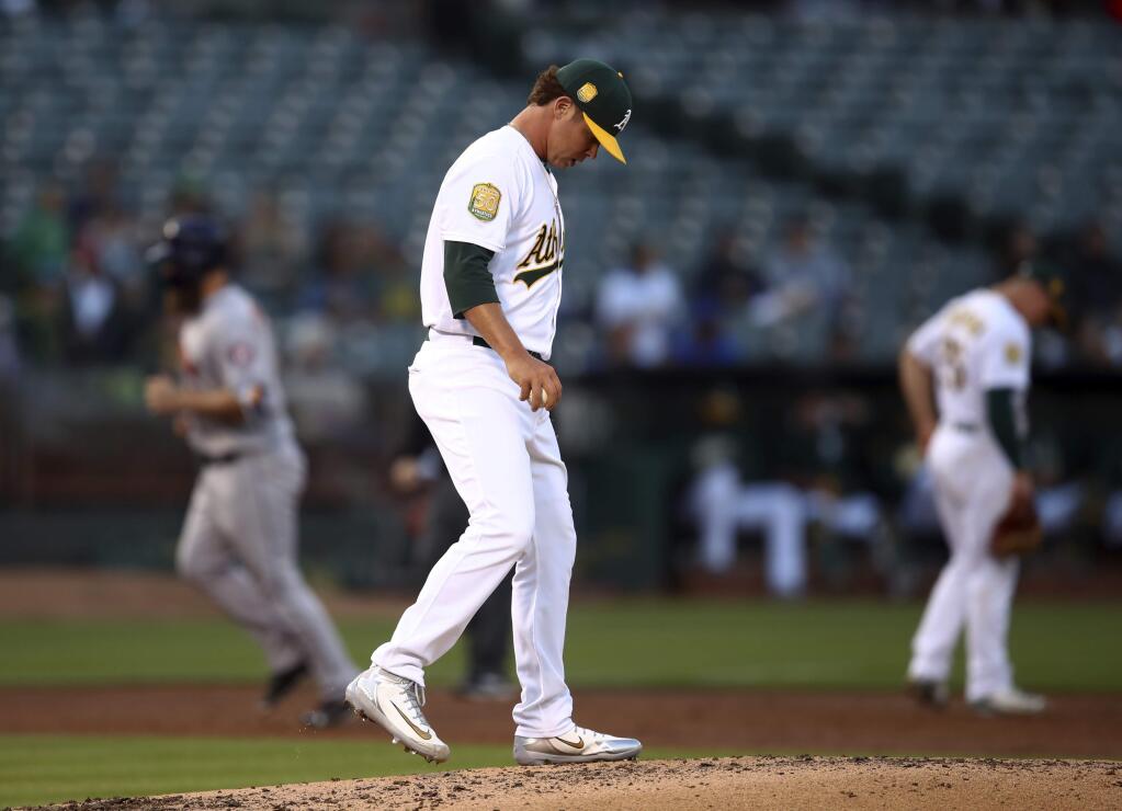 The Oakland Athletics' Emilio Pagan, center, walks back to the mound after giving up a three-run home run to the Houston Astros' Evan Gattis, left, during the second inning Wednesday, June 13, 2018, in Oakland. (AP Photo/Ben Margot)