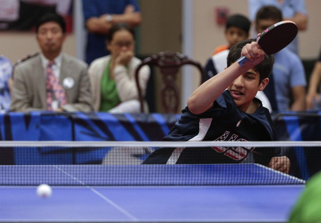In this June 18, 2016, photo, Kanak Jha returns a shot during an exhibition table tennis match in Dunellen, N.J. Jha took up the sport at age 5 with his parents and sister at a recreation center near San Jose, Calif. (AP Photo/Julie Jacobson)