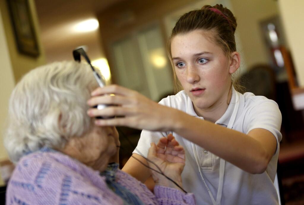 The Healdsburg School seventh grader Julia Donlon, 12, puts headphones on resident Fern Pagni for a student project to build personalized music playlists for residents at Healdsburg Senior Living Community in Healdsburg, California on Monday, November 24, 2014. (BETH SCHLANKER/ The Press Democrat)
