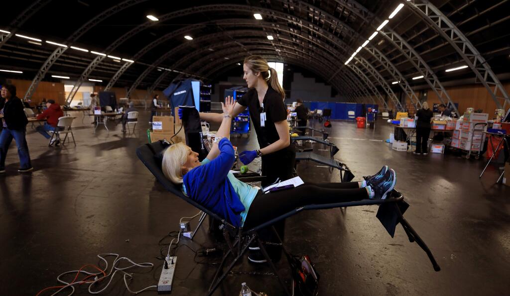 Blood donor Lisa Powell of Santa Rosa finishes up donating blood as Whitney Powell of Vitalant gives her directions after taking the needle out, Friday, March 27, 2020 at the Sonoma county Fairgrounds in Santa Rosa. (Kent Porter / The Press Democrat) 2020