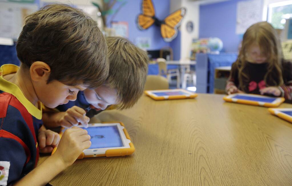 Tablets are portals to a million possibilities. But some teachers are asking if the benefits offset the cost. (STEPHAN SAVOIA / Associated Press)