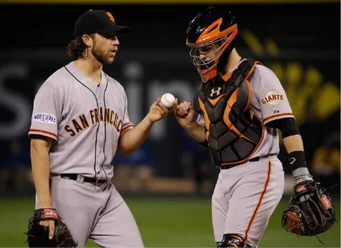 San Francisco Giants pitcher Madison Bumgarner, left, talks with catcher Buster Posey during the second inning of Game 1 of baseball's World Series against the Kansas City Royals Tuesday, Oct. 21, 2014, in Kansas City, Mo. (AP Photo/Matt Slocum )