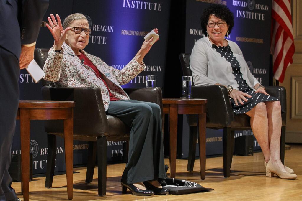 FILE - In this Sept. 25, 2019 file photo, Supreme Court Justice Ruth Bader Ginsburg, left, holds up her hands as she and Supreme Court Justice Sonia Sotomayor arrive to applause for a panel discussion celebrating Sandra Day O'Connor, the first woman to be a Supreme Court Justice, at the Library of Congress in Washington. A month before the Supreme Court takes up cases over his tax returns and financial records, President Donald Trump on Tuesday made the unusual suggestion that two liberal justices should not take part in those or any other cases involving him or his administration. The remarks critical of Justices Ruth Bader Ginsburg and Sonia Sotomayor came during a news conference in India, where Trump was wrapping up a 36-hour visit. (AP Photo/Jacquelyn Martin)