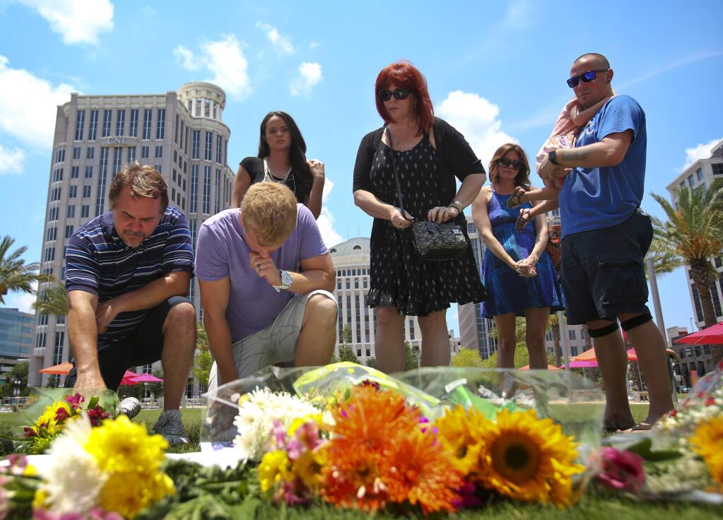 Richie Compton, left, and Erik Winger kneel at a makeshift memorial for the victims of the Pulse nightclub shooting outside of the Dr. Phillips Performing Arts Center on Monday , June 13, 2016. They were paying respects to their friend Shane Tomlinson who was one of the many killed in the mass shooting. (Jacob Langston/Orlando Sentinel via AP)