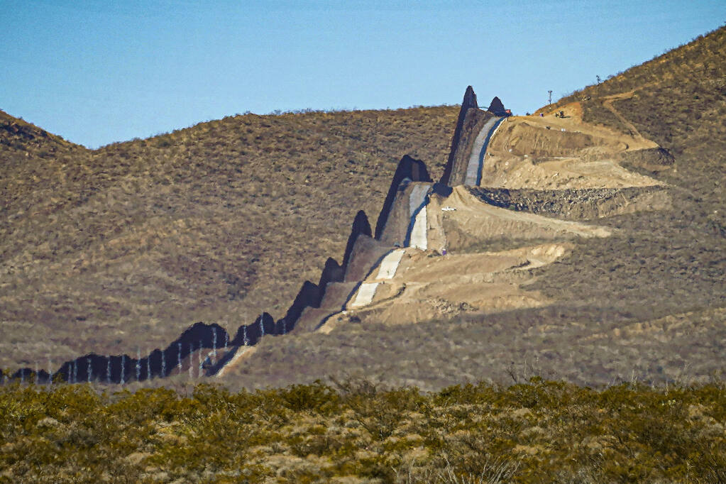 FILE - A U.S. government-built section of border wall snakes through the Sonoran Desert just west of the San Bernardino National Wildlife Refuge, separating Mexico, left, and the United States, Dec. 9, 2020, in Douglas, Ariz. A prosecutor told jurors in closing arguments at a criminal trial, Tuesday, May 31, 2022, that there is overwhelming evidence that organizers of a "We Build The Wall" campaign to raise money for a wall along the U.S. southern border defrauded investors. (AP Photo/Matt York, File)