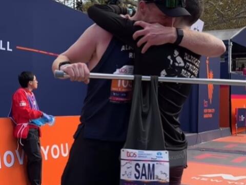 This screenshot from a video shows David Chalmers after completing the New York Marathon with the “Sam Norton” bib prominently pinned onto a shirt hung on a pole carried by himself and Norton’s friend and running coach, Victor Zeitoune. (@newyorknico / / Instagram)