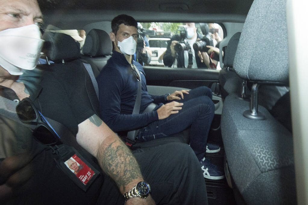 Serbian tennis player Novak Djokovic, center, rides in car as he leaves a government detention facility before attending a court hearing at his lawyers office in Melbourne, Australia, Sunday, Jan. 16, 2022. A federal court hearing has been scheduled for Sunday, a day before the men's No. 1-ranked tennis player and nine-time Australian Open champion was due to begin his title defense at the first Grand Slam tennis tournament of the year. (James Ross/AAP via AP)