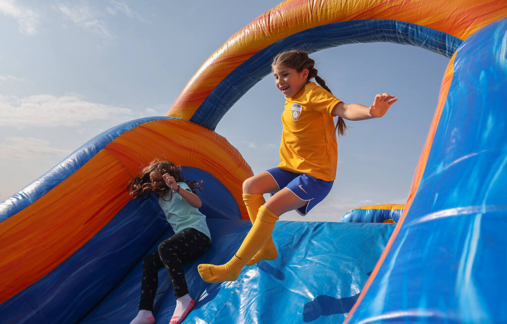 Taylor Sacheli, 9, right, races Riley Schalich, 8, through an inflatable obstacle course during Santa Rosa United Soccer Club’s Fall Festival in Santa Rosa on Wednesday, Sept. 14, 2022.  (Christopher Chung/The Press Democrat)