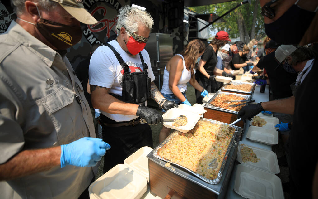 Guy Fieri plates food he and his employees cooked as volunteers put together meals for those working to contain the LNU Lightning Complex fires, Friday, Aug. 28, 2020, at the Calistoga Fairgrounds. (Kent Porter / The Press Democrat) 2020