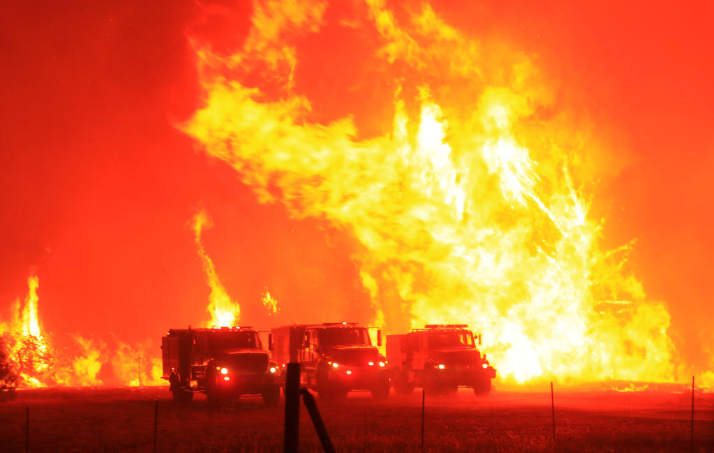 Firefighters took refuge in their trucks in a cleared field as the Hennessey fire jumped Knoxville Berryessa Road, Tuesday, Aug. 18, 202. (Kent Porter / The Press Democrat) 2020