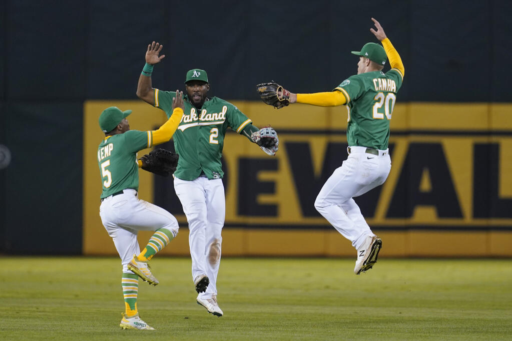 The Oakland Athletics’ Tony Kemp, from left, celebrates with Starling Marte and Mark Canha after the Athletics defeated the Texas Rangers in Oakland on Friday, Sept. 10, 2021. (Jeff Chiu / ASSOCIATED PRESS)